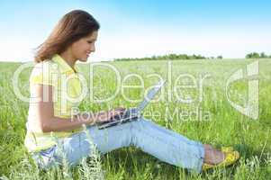 pretty woman with laptop on the green grass