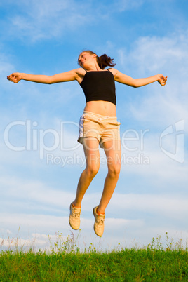 happy young woman is jumping on green grass