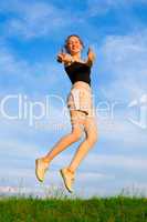 happy young woman is jumping on green grass