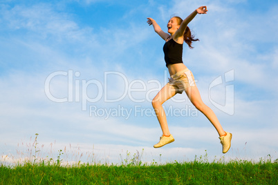 happy young woman is jumping on green grass