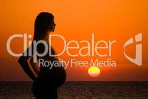 pregnant woman silhouette on sea sunset