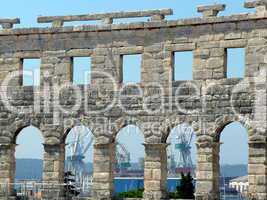 Croatia. Istria. Pula. Seaport cranes through windows of the Arena of Pula