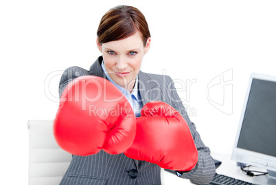Confident businesswoman punching with boxing gloves
