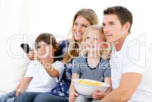 Smiling family watching a film at television