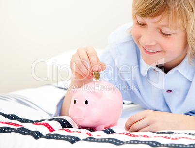 Cute boy putting a coin in a piggybank