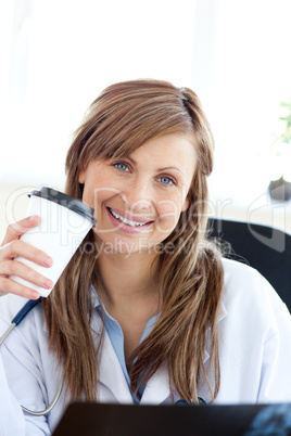 Happy female doctor drinking