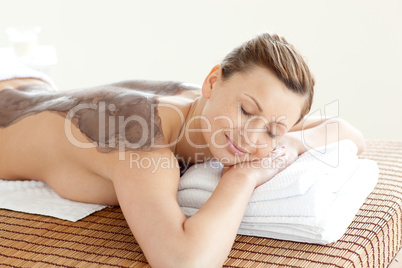 Radiant woman enjoying a mud skin treatment