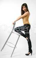 Woman in jeans with stool, side view