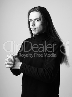 Watchful young man with long hair in black