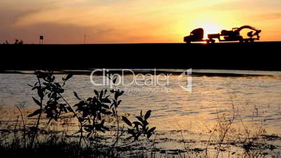 Lake and cars silhouettes against sunset