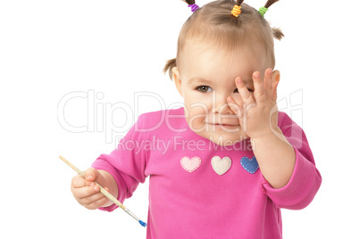 Little girl with paintbrush clasping hand to cheek