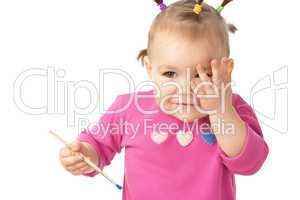 Little girl with paintbrush clasping hand to cheek