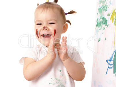 Little girl play with paints, clapping her hands