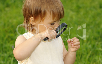 Child looking at snail through magnifying glass