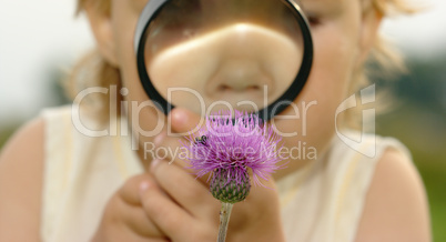 Child looking at flower through magnifying glass