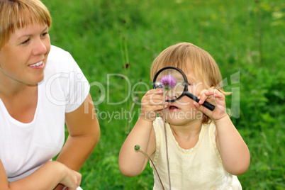 Child looking at flower through magnifying glass