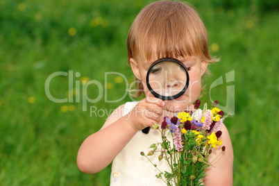 Child looking at flowers through magnifying glass