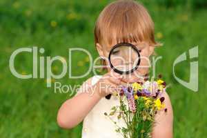 Child looking at flowers through magnifying glass