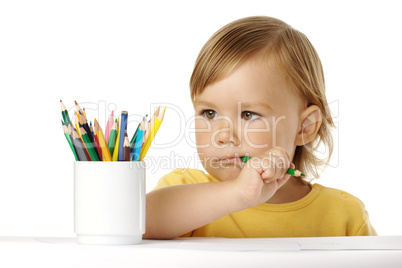 Child bites green crayon and thinks about ideas