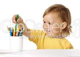 Child picking green crayon from the cup