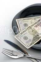 Dollars on plate with fork and knife