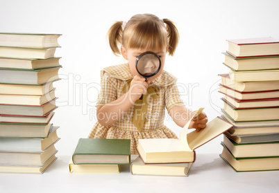 Little girl looking at book through magnifier