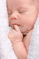 Cute newborn sleeps wrapped in white blanket