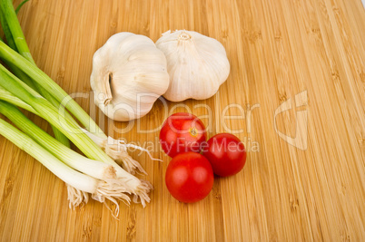 Green Onions, Tomatoes, and Garlic on Cutting Board