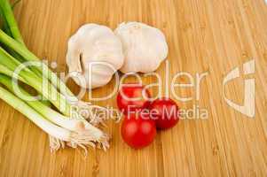 Green Onions, Tomatoes, and Garlic on Cutting Board