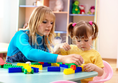 Teacher and preschooler play with building bricks