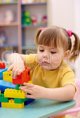 Little girl play with building bricks in preschool