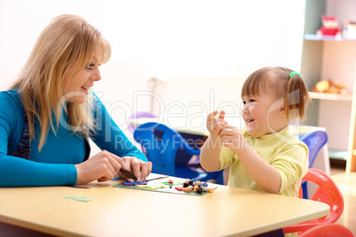 Teacher and little girl play with plasticine