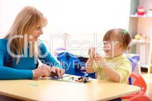 Teacher and little girl play with plasticine