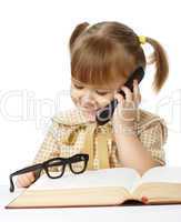 Cute little girl with book talking to a cell phone