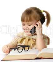 Cute little girl with book talking to a cell phone