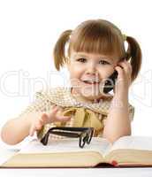 Happy little girl with book and a cell phone