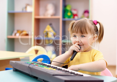 Girl play on a piano and sing in microphone