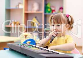 Girl play on a piano and sing in microphone