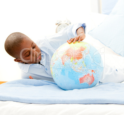 Cute little boy playing with a terrestrial globe