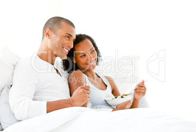 Loving couple having breakfast lying on their bed