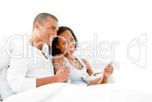 Loving couple having breakfast lying on their bed