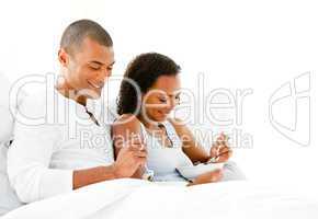 Smiling couple having breakfast lying on their bed