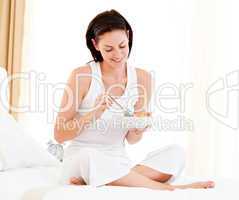 Young woman having breakfast sitting on her bed