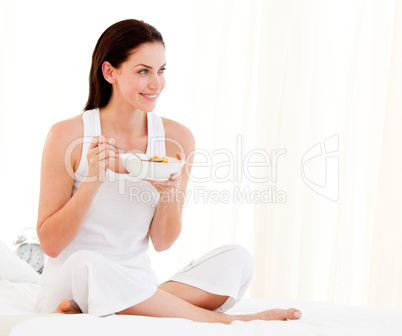 Jolly woman having breakfast sitting on her bed