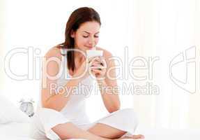 Relaxed woman drinking a coffee sitting on her bed