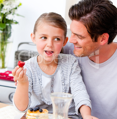 Smiling father and his daughter having breakfast together