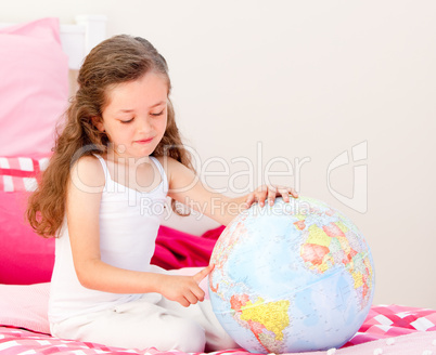 Adorable little girl holding a terrestrial globe sitting on her