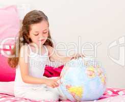 Adorable little girl holding a terrestrial globe sitting on her