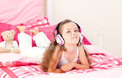 Cute little girl listening music lying on her bed