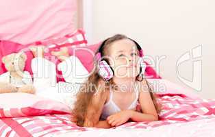 Cute little girl listening music lying on her bed